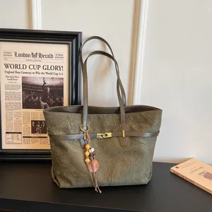 Detailed shot of olive green tote bag with unique wood bead pendant and sleek strap design.