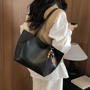 Vista detallada de bolso tote negro minimalista de cuero PU con colgante para estilo diario.