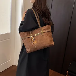 Detail view of brown suede tote bag, large capacity, elegant shoulder strap, chic metal clasp.