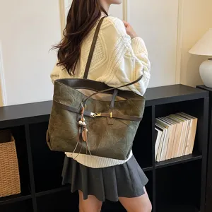 Detailed shot of olive green suede tote bag, featuring chic shoulder strap and metal charm.