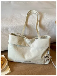 Dettaglio di borsa tote beige casual che mostra trama del tessuto e ciondolo stella.
