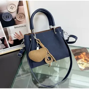 Vista dettagliata della elegante borsa a mano blu scuro con ciondolo a cuore e tracolla.