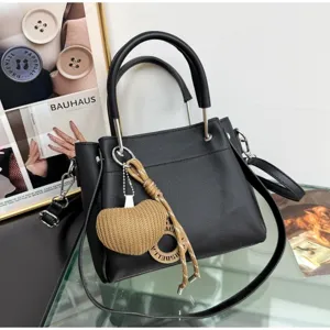 Borsa a tracolla nera di grande capacità con manico e ciondolo a cuore intrecciato.
