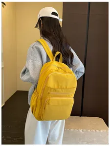Close-up view of the casual yellow backpack showing multi-pocket design and durable fabric.
