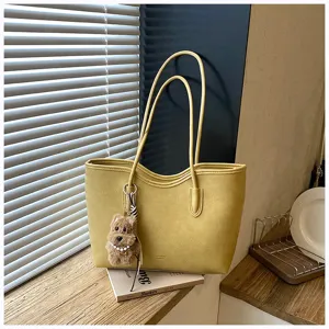 Κοντινό πλάνο κίτρινης δερμάτινης τσάντας tote με μπρελόκ σκύλου, κομψή λεπτομερής σκηνή.