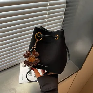 Einfallsreiche schwarze Wildleder-Beuteltasche mit Kordelzug und Kleeanhänger.