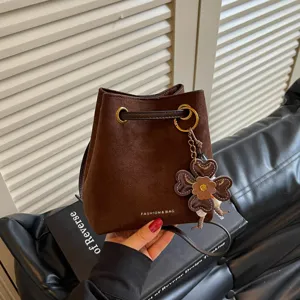 Detailansicht der braunen Wildleder-Beuteltasche mit schickem Kleeblatt-Anhänger und Kordel.