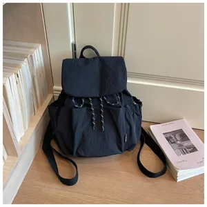 Vue détaillée du sac à dos en toile noire avec poche avant et fermeture par cordon de serrage.