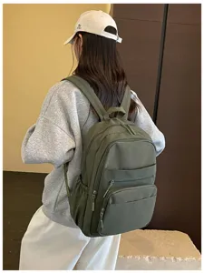 Detail view of the green casual travel backpack showing multi-pocket design and strap.