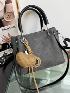 Elegante borsa a tracolla grigia strutturata con manici e ciondolo intrecciato chic.
