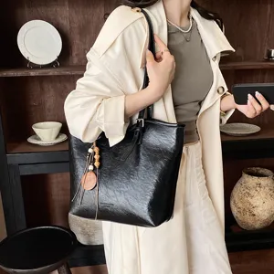 Elegante bolso tote de cuero negro, diseño monocolor minimalista para trabajo y uso diario.