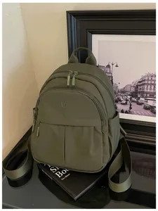 Detail view of casual olive green backpack showing multi-pocket design and texture detail.