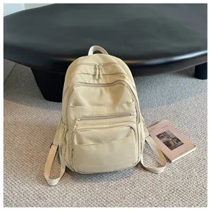 Close-up detail shot of a multi-pocket casual beige backpack in a modern minimalist setting.