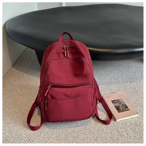 Detail view of the burgundy casual backpack showcasing multiple front zipper pockets and durable straps.