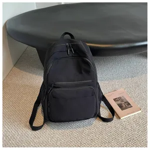 Close-up detail of the black casual backpack featuring multiple secure zippered compartments.