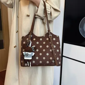 Detalle de bolso de hombro marrón con lunares, bolso elegante de cercanías con lindo colgante de oso.