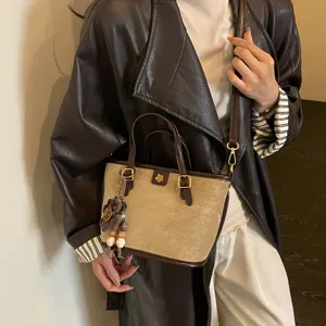 Retro suede bucket bag detail shot, vintage brown PU leather trim, chic flower charm pendant.