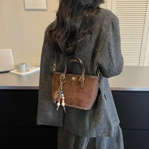 Detailed view of retro brown suede shoulder bucket bag with elegant flower pendant and charms.