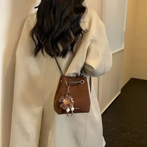 Stilvolle braune Eimer Tasche für Damen, Retro Wildleder Umhängetasche mit süßem Blumenanhänger.