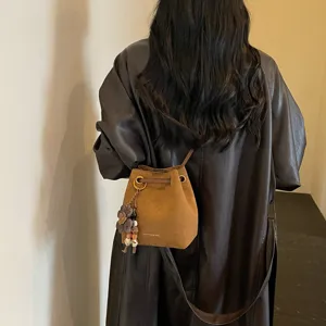 Retro braune Wildleder Eimer Tasche mit Blumen Anhänger als modische Umhängetasche Detail Ansicht.