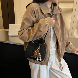 Detailansicht der stylischen schwarzen Beuteltasche mit Anhänger, getragen vom Model.