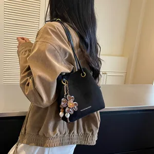 Detailansicht der schwarzen Eimer Tasche mit niedlichem Blumenanhänger für Damen.