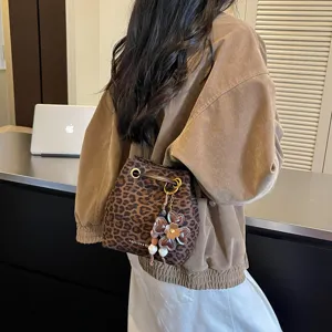 Detailansicht einer stilvollen Leoparden-Eimer Tasche mit Kordelzug und Blumenanhänger.