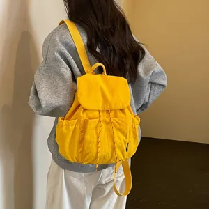 Vue détaillée d'un sac à dos en tissu jaune, montrant le port au dos et les bretelles.