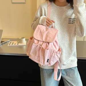 Vue détaillée du sac à dos rose décontracté avec poches avant et cordon de serrage quotidien.