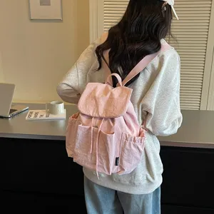 Vue détaillée du sac à dos en toile rose léger et décontracté porté par le modèle, chic.