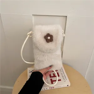 Close-up of a fluffy faux fur crossbody phone bag with a cute brown knit flower accent.