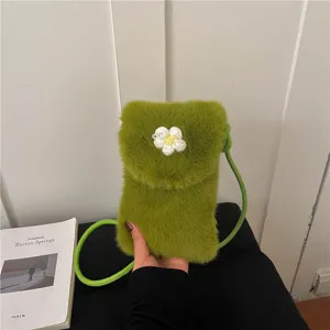 Detail view of green plush phone bag featuring cute handmade crochet flower and crossbody strap.