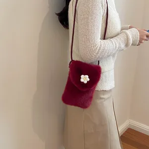 Detailed shot of a stylish burgundy plush crossbody phone bag with cute white flower decor.