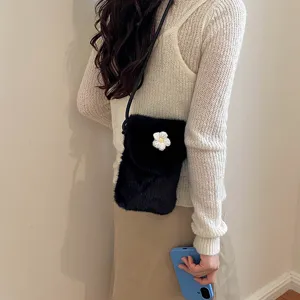 Close-up of stylish black faux fur crossbody phone bag with white daisy flower detail.