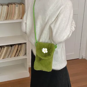 Green plush cross-body phone bag detail shot featuring a cute white flower decoration.