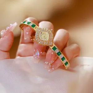 Close-up detail of retro green crystal quartz watch with elegant gold bangle strap and intricate bezel.