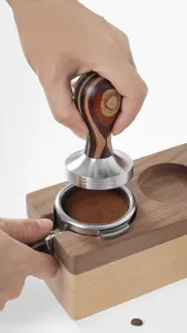 Tamper à café en acier inoxydable avec poignée en bois et base de distribution détail.
