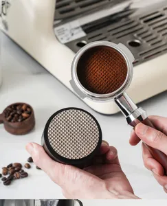 Detailed view of espresso coffee puck screen and portafilter tool for even extraction.