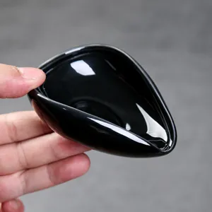 Close-up detail of black ceramic coffee bean measuring spoon with smooth pouring spout.