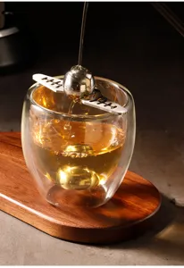 Stainless steel coffee ice ball tool and double wall glass cup detail shot for chilling espresso.