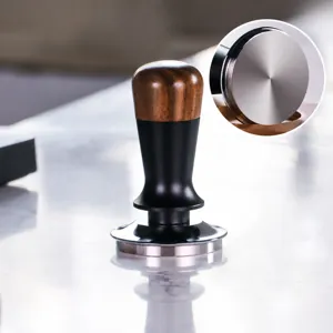 Detailed close-up view showing the solid wooden handle and stainless steel flat base coffee tamper.