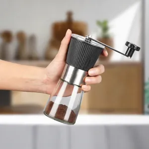 Macinacaffè manuale con contenitore in vetro trasparente e corpo in acciaio inox per uso domestico.