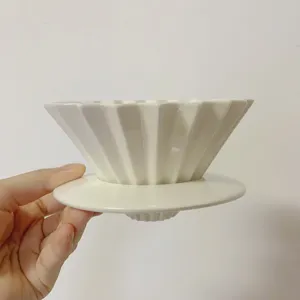 Detailed shot of white ceramic origami coffee dripper, conical pour over filter cup detail.