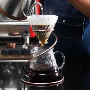 Detailed view of copper spiral coffee dripper stand and glass server set for pour over brewing.