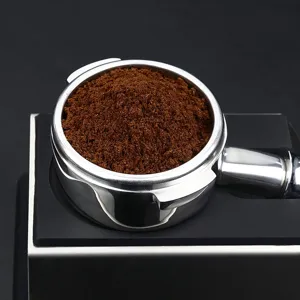 Stainless steel 58mm espresso portafilter coffee machine handle with ground coffee powder.