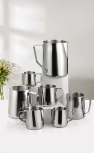 Detailed shot of multiple stainless steel milk frothing pitchers in various sizes on display stands.