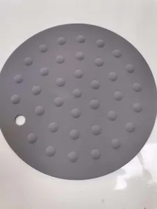 Close up detail van ronde grijze siliconen isolatiemat met reliëf antislip punten en gat.