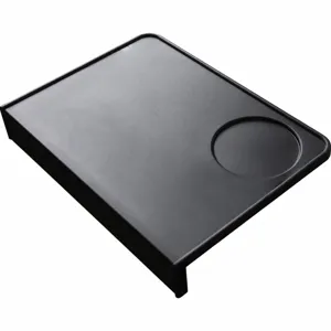 Tapis de tassement a cafe en silicone noir, detail d'angle, accessoire espresso durable.