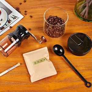 Close-up detail of the manual coffee grinder with coffee beans and accessories on wood.