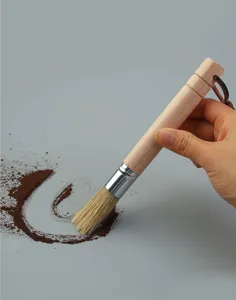Close-up of wooden handle coffee grinder cleaning brush with natural bristles in action.